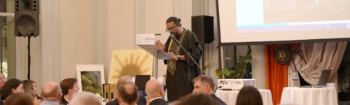 Un intervenant au pupitre s’adresse aux personnes attablées lors de la soirée de gala HFE.